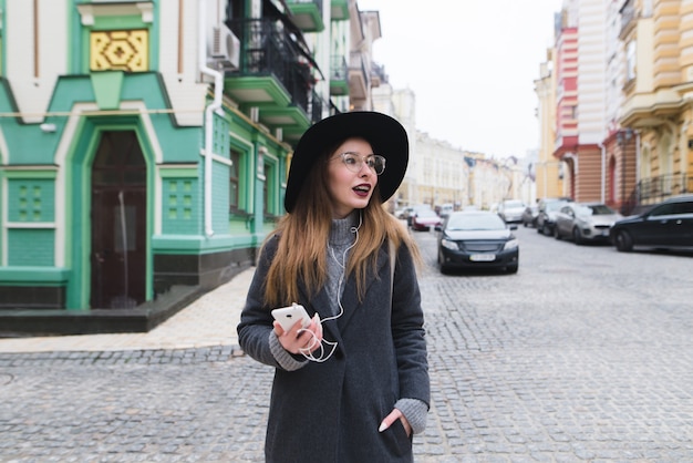 Turista della donna alla moda passeggiando per le strade del centro storico e sorridente. ragazza che cammina per le strade