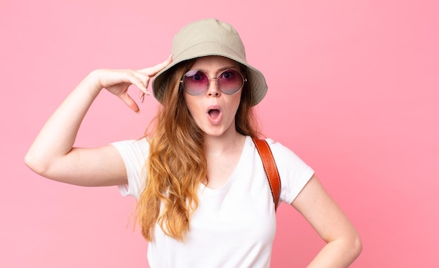 Turista della donna graziosa della testa rossa che sembra sorpreso realizzando una nuova idea o concetto di pensiero