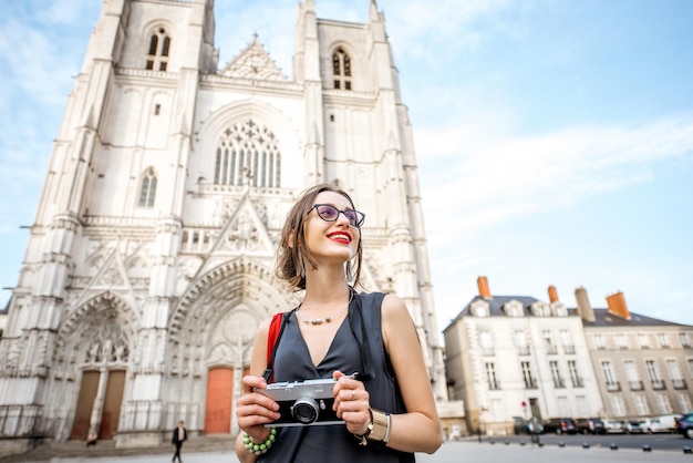 Turista della giovane donna che cammina con la macchina fotografica sulla piazza Saint Pierre vicino alla cattedrale nella città di Nantes