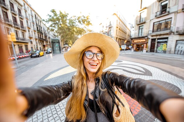 Turista della giovane donna che fa la foto del selfie che sta sulla via centrale con le mattonelle variopinte famose nella città di Barcellona