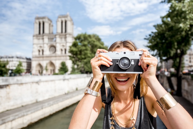 Turista della giovane donna che fotografa con la macchina fotografica che sta davanti alla cattedrale famosa di Notre Dame a Paris