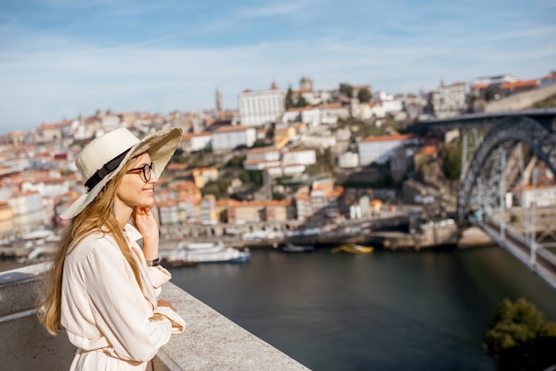 Turista della giovane donna che gode del bello fondo di paesaggio urbano con il ponte famoso nella città di Porto, Portugal