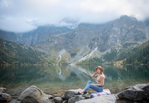 Turista della giovane donna che si siede sul picco di montagna e sulle belle montagne