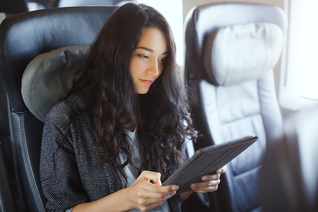 Turista della giovane donna che utilizza il suo computer tablet durante il viaggio in treno. Applicazione di viaggio