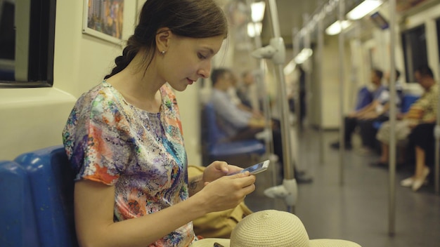 Turista della giovane donna che viaggia in metropolitana e che guarda nella mappa allo smartphone nella metropolitana di Bangkok