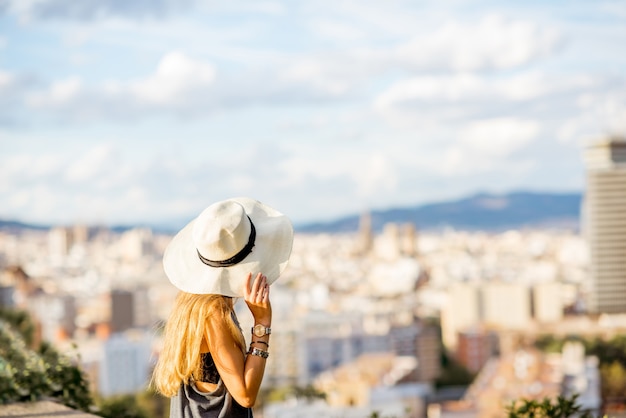 Turista della giovane donna in cappello che gode della grande vista di paesaggio urbano su Barcelona