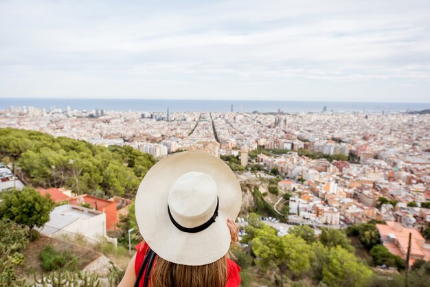 Turista della giovane donna in cappello che gode della grande vista di paesaggio urbano su Barcelona