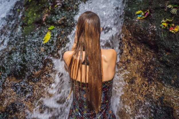 Turista della giovane donna nelle sorgenti sante Sebatu a Bali