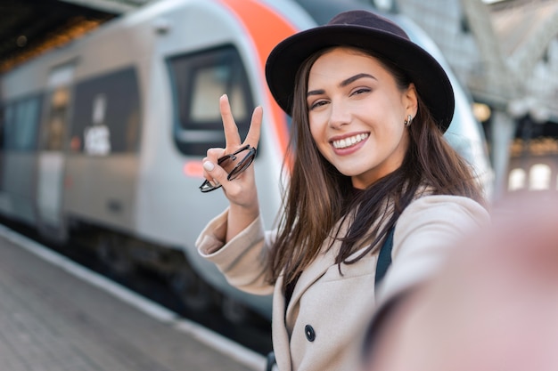 Turista della ragazza prende selfie alla stazione ferroviaria