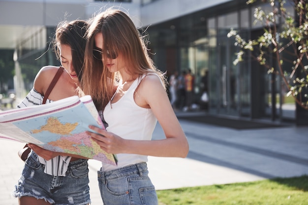 Turista di due donne con mappa in visita in una nuova città e alla ricerca di una strada per l'hotel.