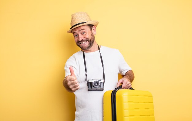 Turista di mezza età che si sente orgoglioso, sorride positivamente con i pollici in su. concetto di viaggio