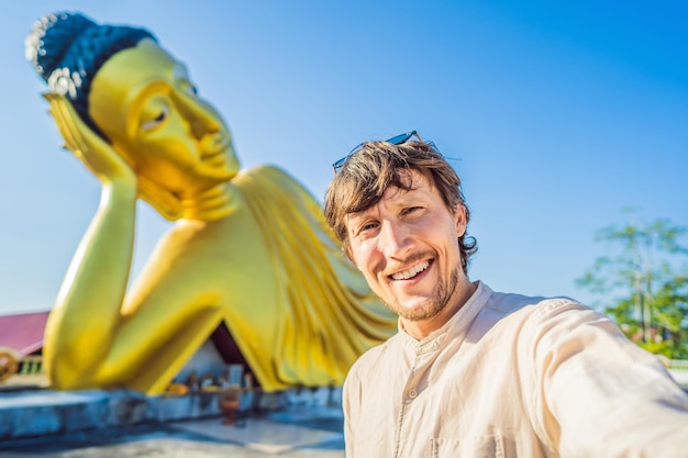 Turista felice dell'uomo sullo sfondo della statua del Buddha sdraiato