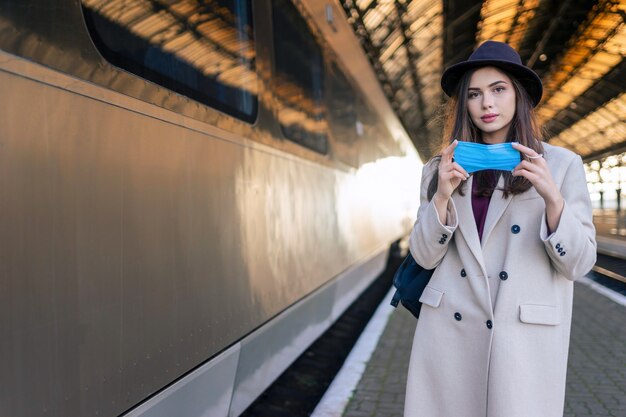 Turista femminile alla stazione ferroviaria che indossa la maschera