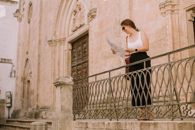 Turista femminile con una mappa della città vicino alla chiesa di San Francesco d'Assisi a Ostuni Italia