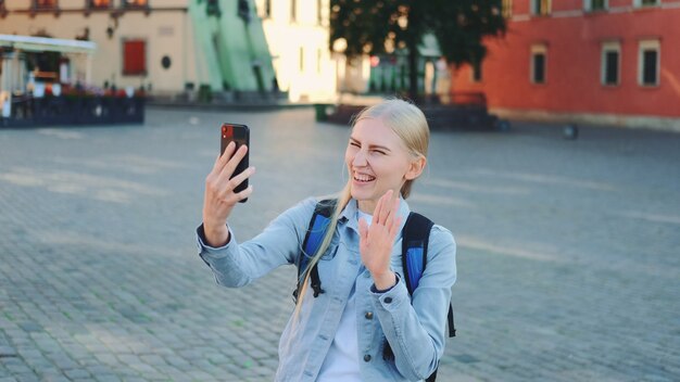 Turista femminile grazioso che effettua videochiamata sullo smartphone dal luogo della sua visita