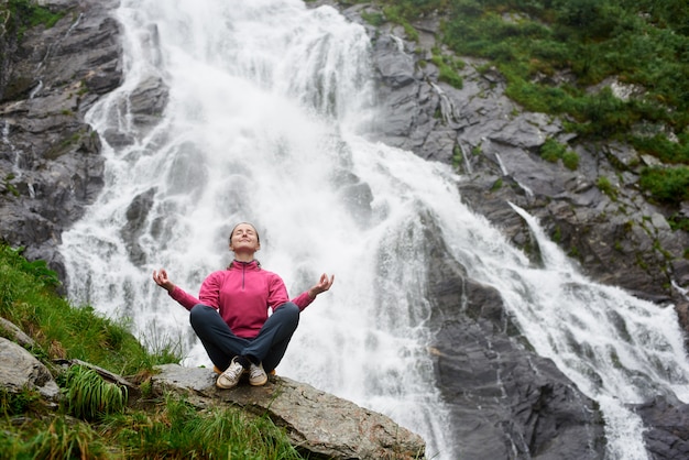 Turista femminile osservando bella cascata in montagna