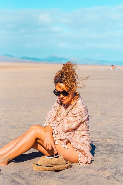 Turista femminile rilassarsi sotto il sole in estate vacanza giorno di vacanza in spiaggia utilizzando il telefono cellulare Attraente donna adulta godersi la connessione all'aperto Free solo single lady persone in attività turistiche