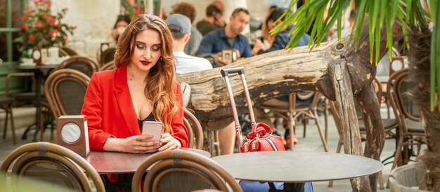 Turista giovane caucasica in una giacca rossa guardando smartphone