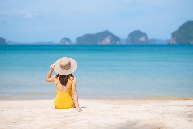 Turista in costume da bagno giallo e cappello viaggiatore felice che prende il sole a Paradise Beach sulle isole destinazione Wanderlust Asia Viaggi vacanze estive tropicali e concetto di vacanza