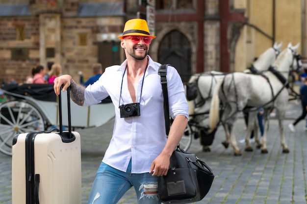Turista in vacanza bel giovane in viaggio d'affari che cammina con i suoi bagagli in viaggio per strada
