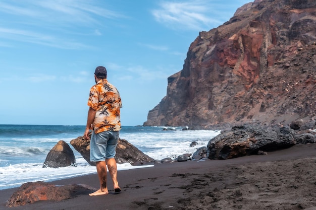 Turista in vacanza sulla spiaggia di sabbia vulcanica nera di Ingles a Valle Gran Rey su La Gomera Isole Canarie