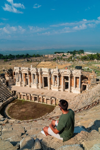 Turista irriconoscibile seduto sulla schiena godendo della vista del famoso teatro di Hierapolis a Pamukkale
