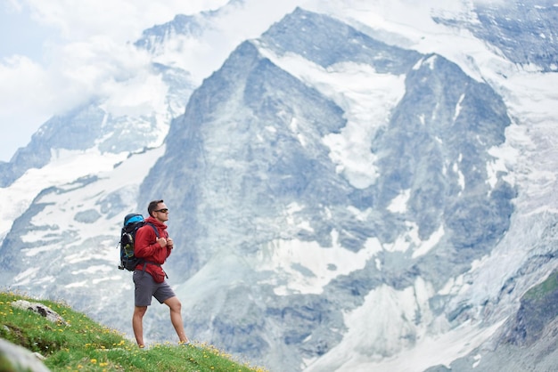 Turista maschio che scala le scogliere rocciose innevate delle belle Alpi di Penning in Svizzera