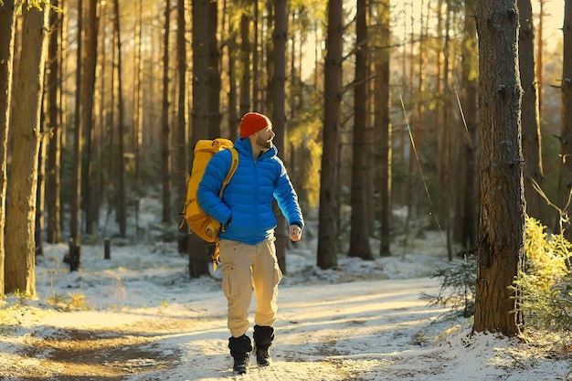 turista nella foresta invernale / il ragazzo viaggia sullo sfondo di un paesaggio invernale con foresta, neve e alberi