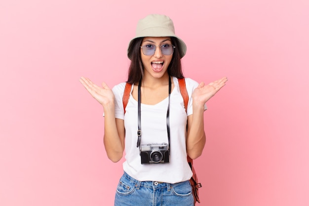 Turista piuttosto ispanico che si sente felice e stupito per qualcosa di incredibile con una macchina fotografica e un cappello