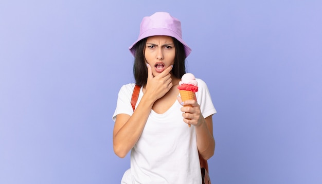 Turista piuttosto ispanico con la bocca e gli occhi spalancati e la mano sul mento e con in mano un gelato