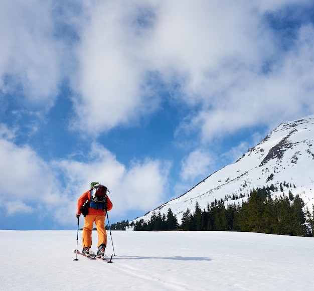 Turista sciatore con zaino su sfondo di cielo azzurro e bellissimo panorama montano