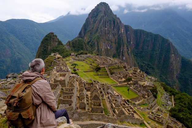 Turista seduto sulla schiena a guardare Machu Picchu Lost City of Inca, Perù. Una delle nuove sette meraviglie del mondo.