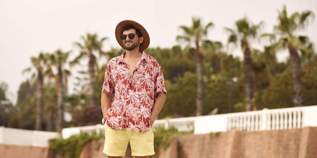 Turista spiaggia uomo all'aperto contro le palme sullo sfondo durante le vacanze estive