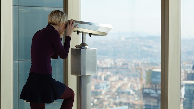 Turista sta guardando attraverso il binocolo sulla città da un punto alto