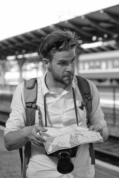 Turista su strada guardando la guida Viaggiatore sulla stazione ferroviaria