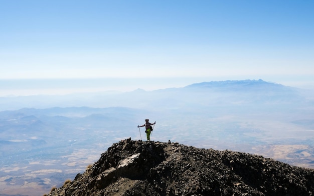 Turista sulla cima della montagna con le mani alzate