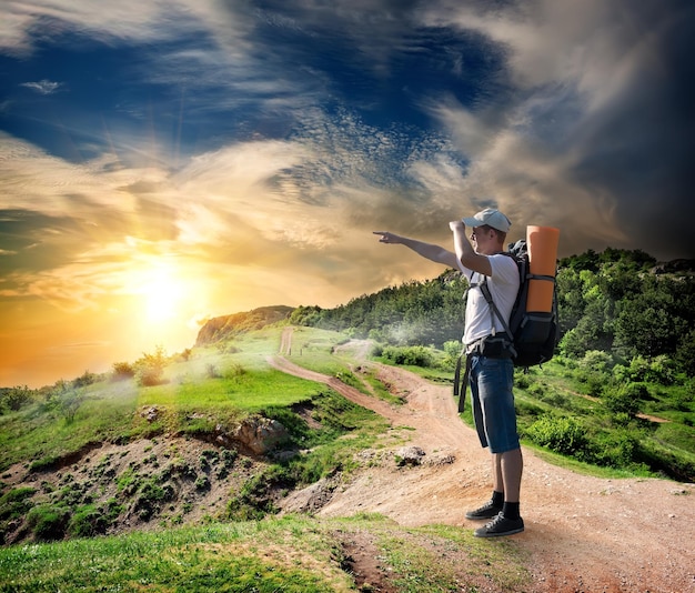 Turista sulla strada in montagna al tramonto