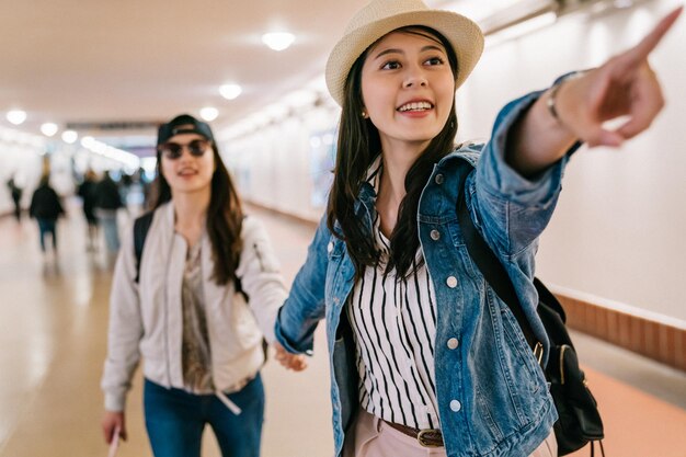 turiste trovarono la piattaforma ed eccitate indicarono il cartello nella stazione di Union in America. Fidanzate donne che viaggiano in America sorridenti gioiose divertendosi in viaggio turistico.