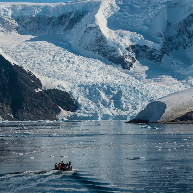 Turisti che guardano un ghiacciaio in Antartide vicino alla Penisola Antartica