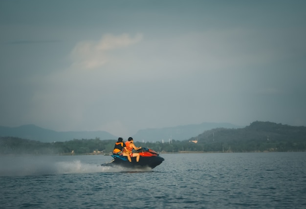 Turisti che guidano moto d'acqua ad alta velocità in mare o fiume con spruzzi d'acqua