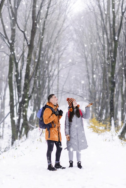 Turisti con zaini che camminano nella foresta innevata invernale ed e