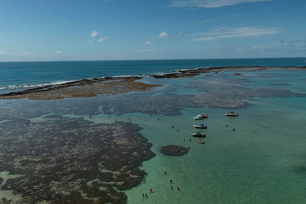 Turisti e piccole imbarcazioni in piscine naturali formate da scogli