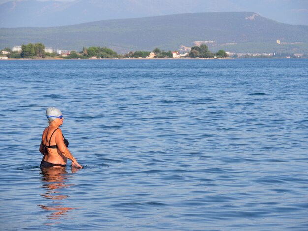 Turisti e vacanzieri nuotano nel Mar Egeo e si rilassano sulla spiaggia in una giornata estiva in Grecia