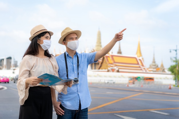 Turisti felici delle coppie asiatiche per viaggiare indossando maschera