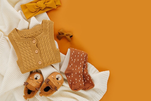 Tutina gialla, calzini e simpatiche ciabatte per bambini con coperta in maglia. Set di vestiti e accessori per neonati. Disposizione piatta, vista dall'alto