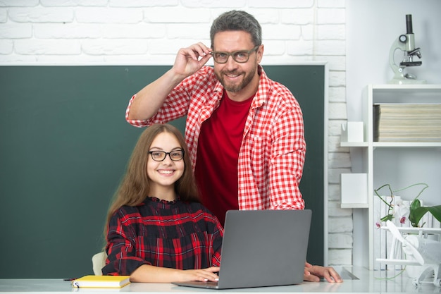 Tutor dell'insegnante che aiuta il bambino della scuola in classe a scuola usando il computer portatile