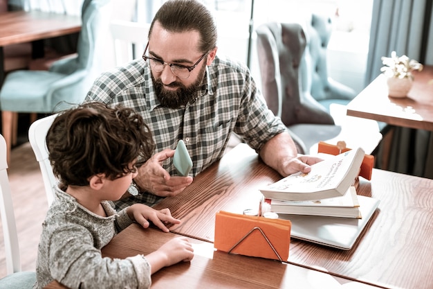 Tutor privato. Tutor privato barbuto dai capelli scuri che insegna a leggere e scrivere a un simpatico bambino in età prescolare