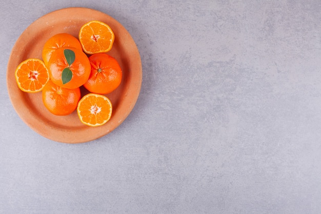 Tutta la frutta arancione con mandarini a fette posizionati sul piatto di argilla.