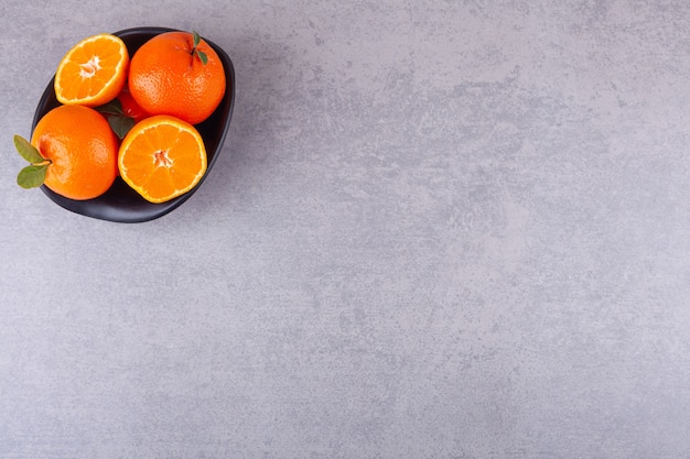 Tutta la frutta arancione con mandarini a fette posti nella ciotola nera.