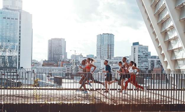 Tutta la lunghezza dei giovani in abbigliamento sportivo che fa jogging mentre si esercita sul ponte all'aperto